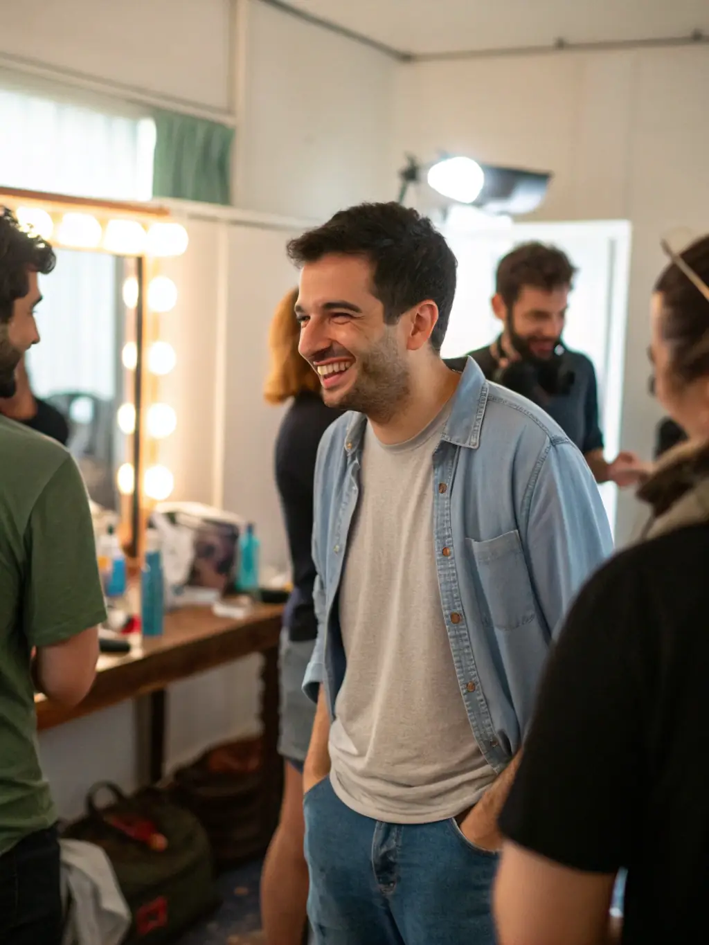 A candid shot of a well-known actress known for her comedic roles, backstage at a comedy event, smiling and interacting with other performers.